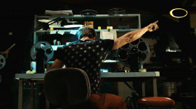A movie doesn't come all on one big reel. It comes on a few. So someone has to be there to switch the projectors, at the exact moment that one reel ends and the next one begins. If you look for them, you can see little dots, come into the upper right corner of the screen. That's the cue for a changeover. He flips the projectors, movie keeps right on going and nobody in the audience has any idea.