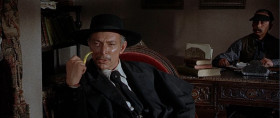 - I'm looking for a first-class bank.
- Oh, but exactly.
- Yeah. The largest and most secure bank in the territory.
- Well, Mr. Mortimer, I want to assure you our bank here has everything, all the safeguards you're looking for.
- I don't doubt that, but I have a large sum to deposit. Now, suppose I'm a bandit.
- A bandit?
- A very dangerous bandit with a gang of killers. Now what would be the most impossible bank for me to rob?
- In your case, the one bank I would suggest is the Bank of El Paso. Not even Indio would dare to attack that one. It's not a bank. It's a fortress there.
- What time's the next train for El Paso?
- 11:30. I'll telegraph to my colleague in the Bank of El Paso that you're going to arrive.
- Thanks.