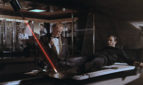 - This is gold, Mr. Bond. All my life, I've been in love with its color, its brilliance, its divine heaviness. I welcome any enterprise that will increase my stock. Which is considerable.
- I think you've made your point, Goldfinger. Thank you for the demonstration.
- Choose your next witticism carefully, Mr. Bond. It may be your last. The purpose of our two previous encounters is now very clear to me. I do not intend
to be distracted by another. Good night, Mr. Bond.
- Do you expect me to talk?
- No, Mr. Bond. I expect you to die. There is nothing you can talk to me about that I don't already know.
- You're forgetting one thing. If I fail to report, 008 replaces me.
- I trust he will be more successful.
- But he knows what I know.
- You know nothing, Mr. Bond.
- Operation Grand Slam, for instance.
- Two words you may have overheard, which cannot possibly have any significance to you or anyone in your organization.
- Can you afford to take that chance?
- You are quite right, Mr. Bond. You are worth more to me alive.
