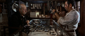- Revolvers!
- Yeah, revolvers.
- Revolvers. Well, here's where I keep the best ones. Here, Remington, Colt, a Root, Smith-Wesson, Colt - navy, Joslyn, another Remington, and this one...
- That's enough.
- Cartridges.
- You wanna try the pistol, step out back.
- Cartridge. How much?
- Twenty dollars
- No.
- Fifty dollars.
- How much?
- A hundred dollars. Two hundred dollars. It's all I've got.